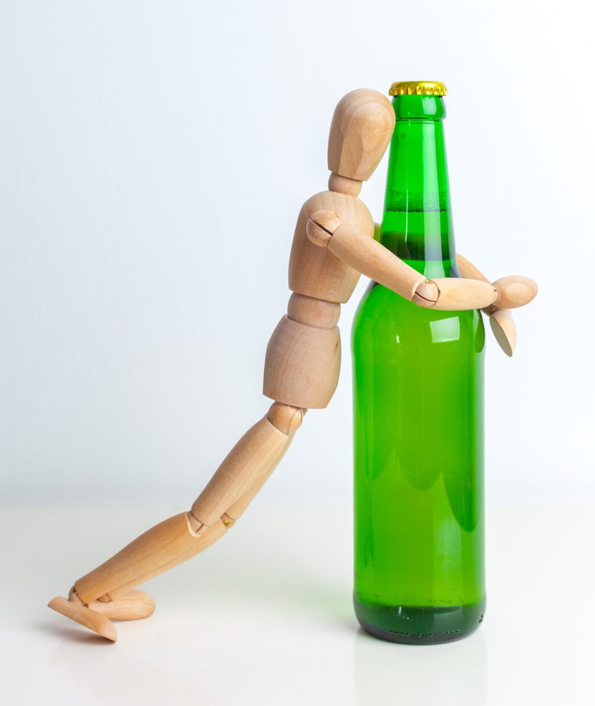 Alcoholism concept. Wooden doll with Alcohol drink