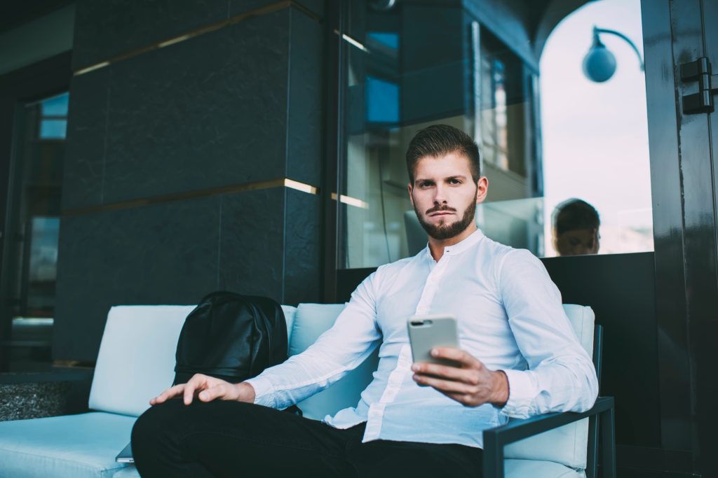 Unemotional man with phone on couch